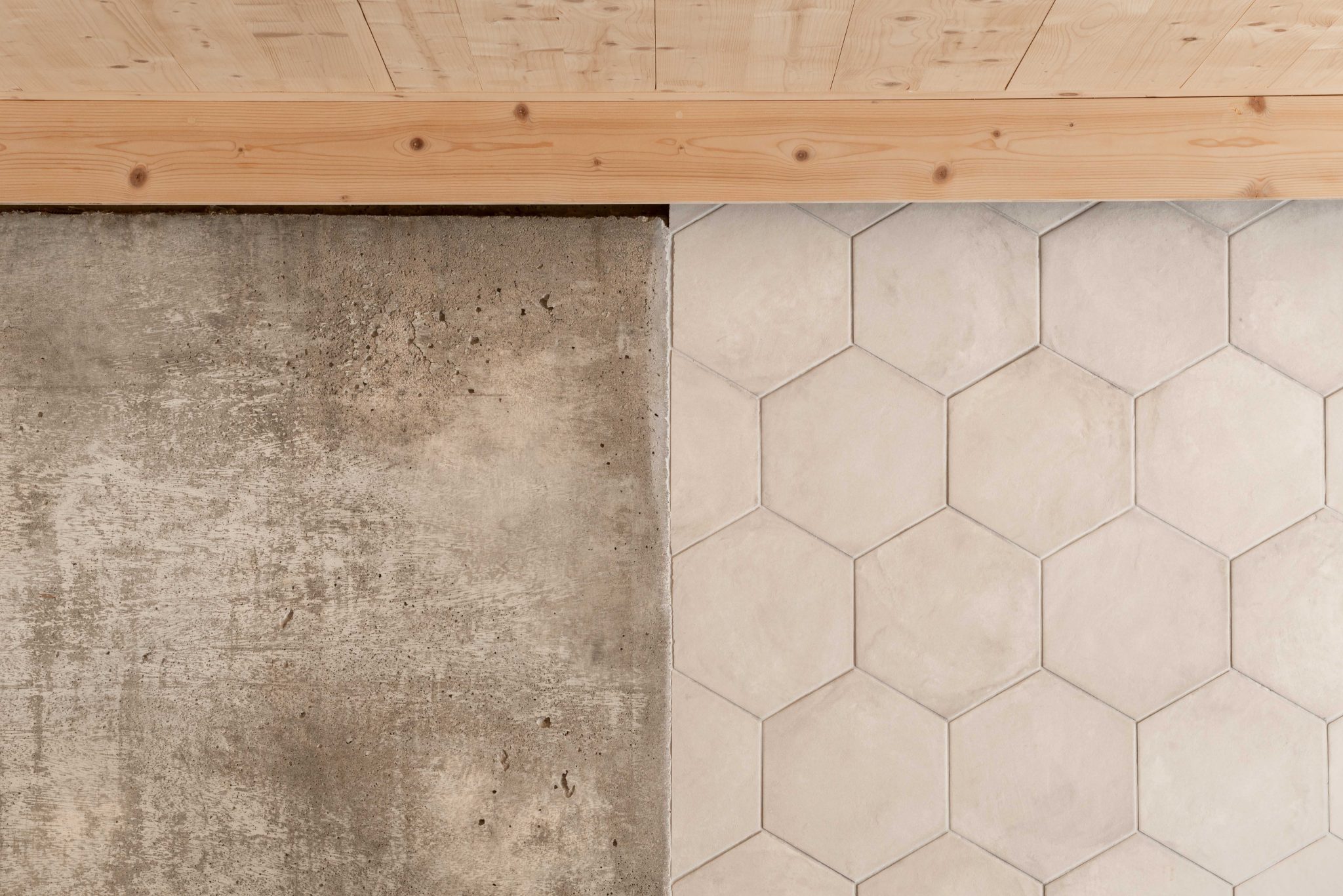 Close-up of natural building materials - polished concrete, pale hexagonal tiles, and timber floorboards - symbolising transformation and craftsmanship in home design.