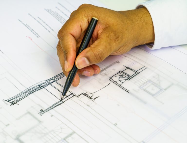 Close-up of an architect reviewing technical drawings - part of the pre-start protection stage to ensure contract clarity, compliance, and site readiness.