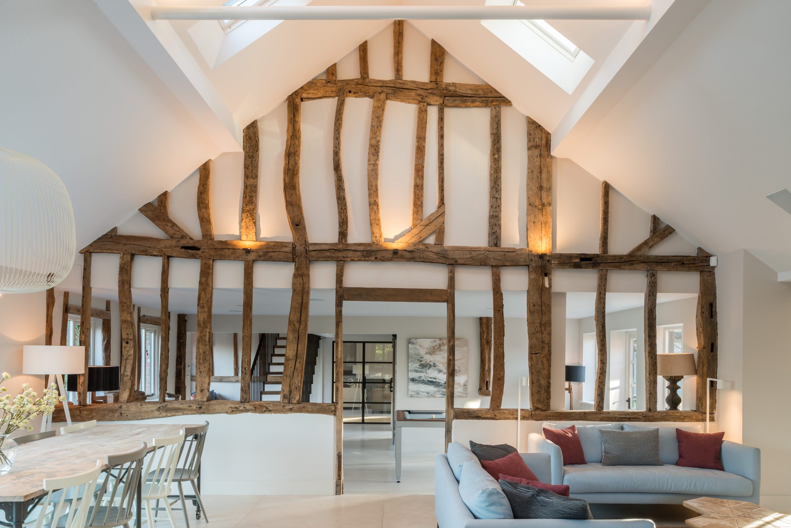Open-plan living room and dining space featuring exposed timber beams and vaulted ceiling in a modern barn conversion